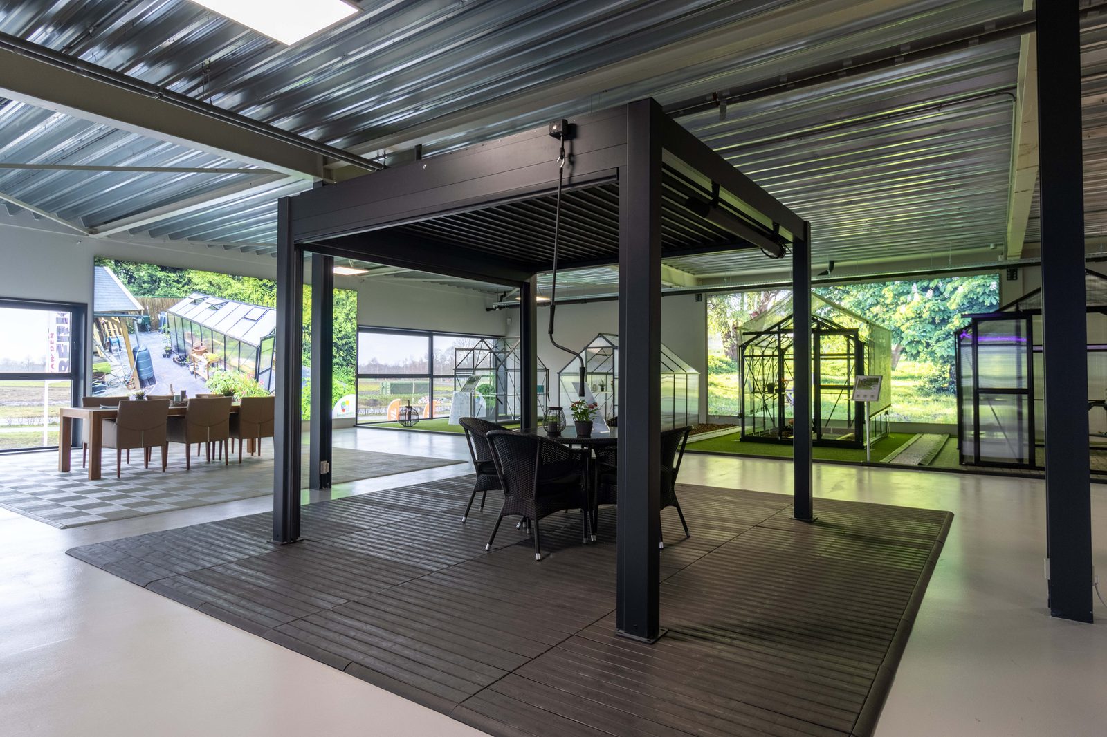 Showroom in Someren met een pergola boven een eettafel en een rij tuinkassen